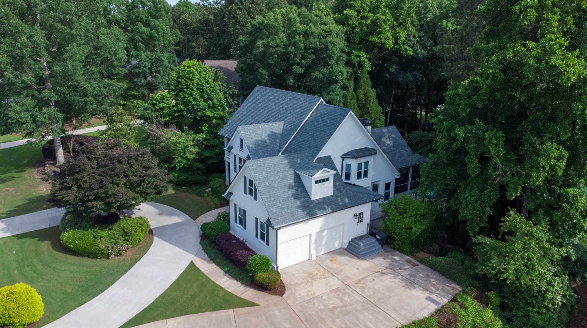 Aerial view of suburban homes with lush greenery and well-maintained gardens.
